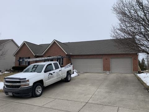 Company truck with ladder parked at brick house